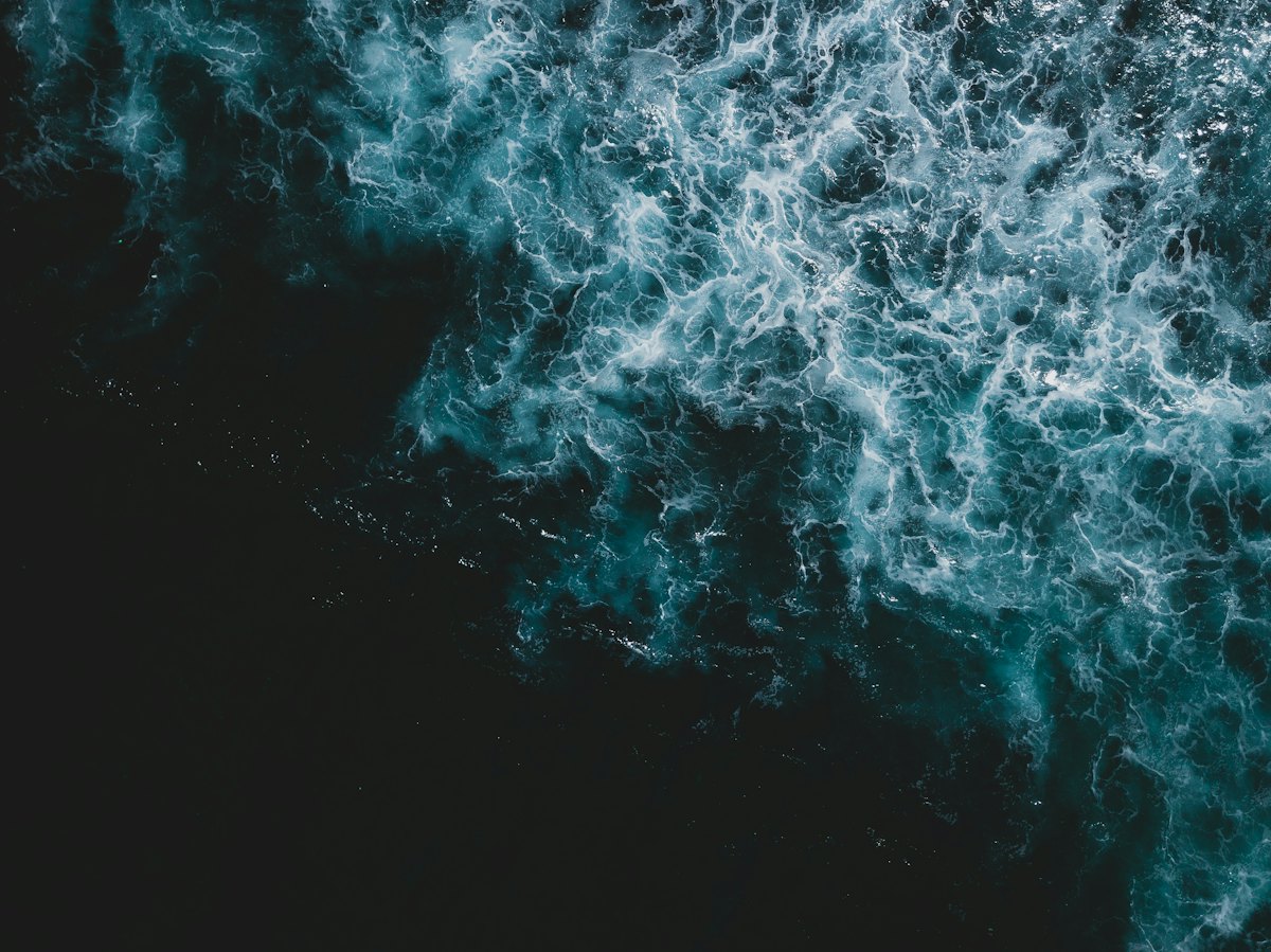 Aerial view of deep open ocean with white sea foam