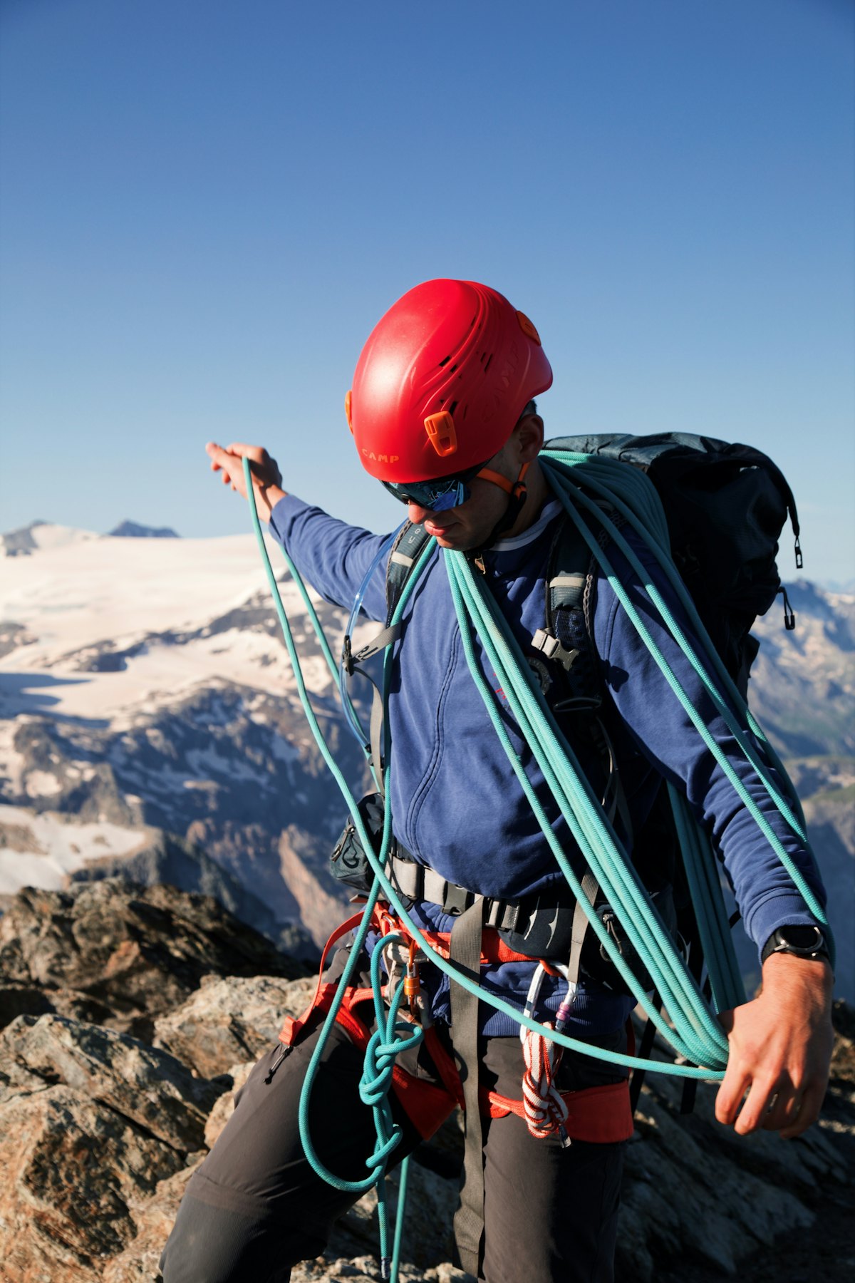 A climber coiling rope on a high mountain ridge